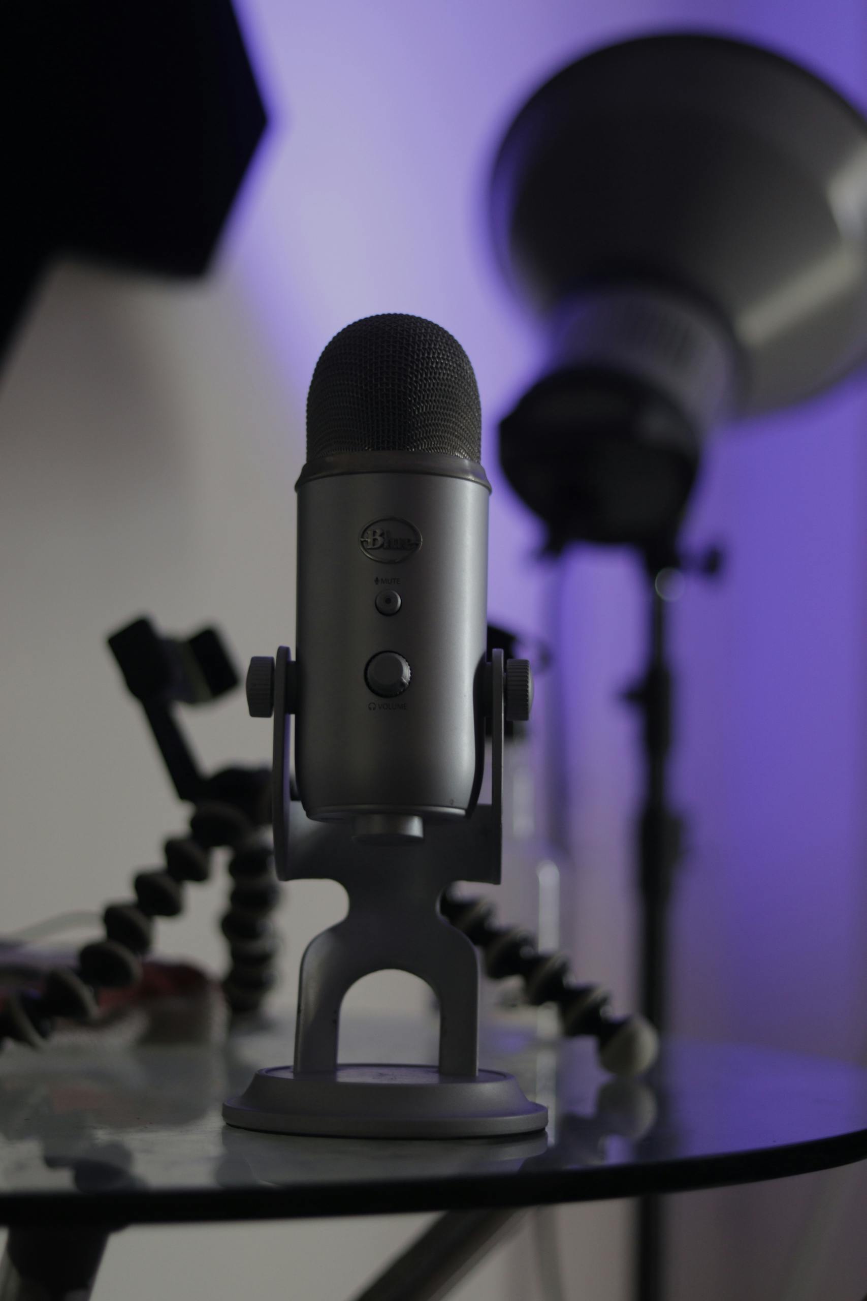 Condenser microphone on a reflective table with studio background lighting.